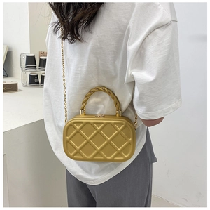 Detail of gold quilted box bag with metallic twist handle and thin chain strap