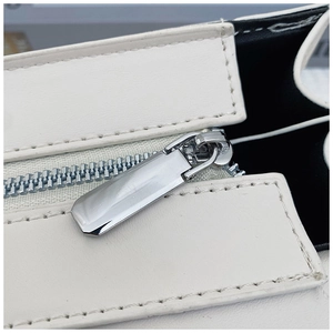 Macro detail of silver metal zipper and precise stitching on beige leather handbag
