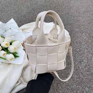 Detail of cream woven bucket bag with drawstring liner and detachable shoulder strap