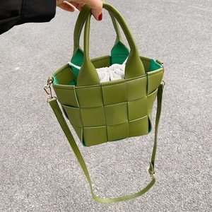 Detail view of grass green woven leather bucket bag with a white drawstring inner pouch