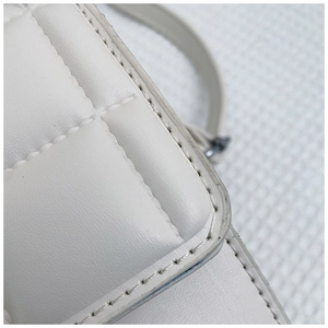 Macro shot of white quilted leather bag showing precise stitching and refined edge texture