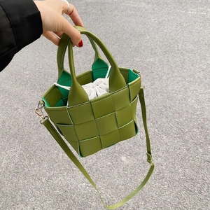 Close-up of green woven leather tote bag with canvas drawstring insert and gold hardware