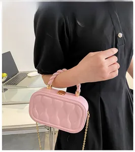 Detailed view of pink textured box bag with braided handle and gold metal chain strap
