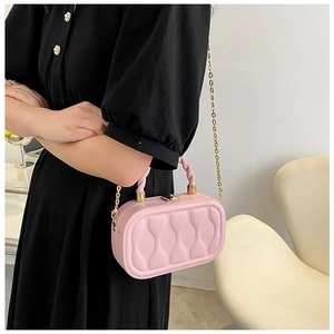 Detail view of pink quilted box bag with woven handle and gold chain strap on a black dress