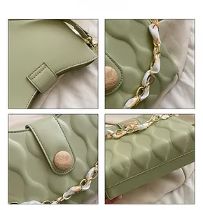 Detail of light green bag showing wavy embossed leather, wooden buckle and silk scarf chain