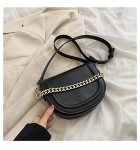 Detail of black semi-circular saddle bag with bold gold chain link and leather strap