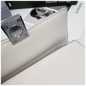 Macro view of white leather bag featuring a silver square magnetic buckle and precise stitching