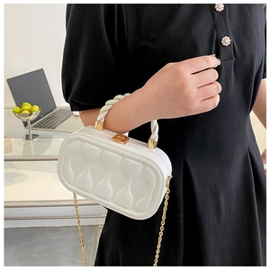 Close-up of white quilted box bag with gold twist lock and woven handle held by model