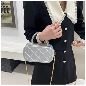 Detail of silver quilted evening clutch with gold chain strap and metallic handle