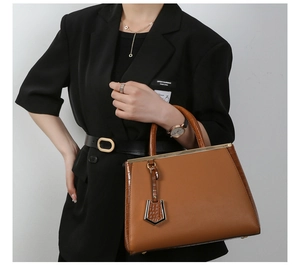 Dettaglio di una borsa grande marrone in pelle con texture coccodrillo e oro