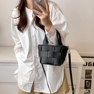Mirror selfie showing black woven tote bag with a cream drawstring pouch insert
