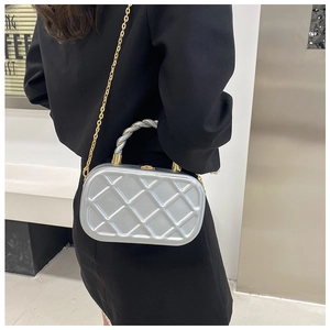 Detail of silver quilted box bag with braided handle and gold chain on black blazer