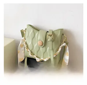 Detail view of mint green handbag featuring wavy quilting and heart print silk scarf