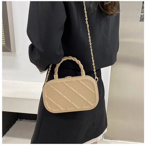 Detail of beige quilted crossbody bag with twisted brown handle and gold chain strap
