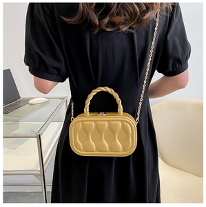 Model showing a mini gold box bag with textured wave quilting and metal chain strap