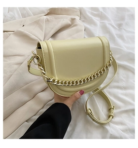Detail of a creamy yellow half-moon saddle bag with a chunky gold chain and leather strap