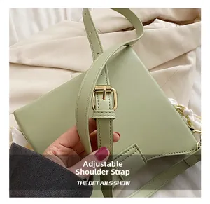 Detail view of adjustable shoulder strap with gold metal buckle on light green bag