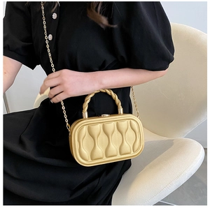 Golden hard shell evening bag with wave texture shown on a black dress with metal chain