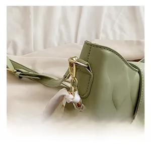 Detail of high-gloss gold metal hook and wave quilted texture on green shoulder bag
