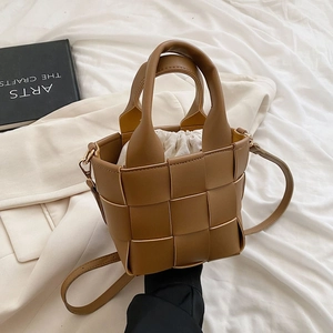 Close-up of woven brown leather bucket bag with white drawstring inner pouch