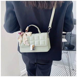 Detail of light green quilted leather bag with silver G-lock and decorative silk scarf