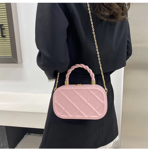 Detailed macro view of pink quilted handbag with gold chain and woven handle texture