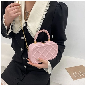 Detail of pink quilted box handbag with gold chain strap and twisted handle on model