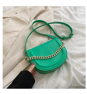 Detail of green saddle bag featuring a bold gold chain on high-quality faux leather