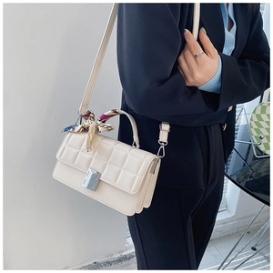 Crossbody bag with square embossed pattern and scarf wrapped handle shown on model