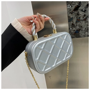 Detailed shot of a silver quilted evening bag with gold chain and metal twist handle