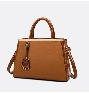 Detail view of dark brown leather handbag with crocodile pattern texture and gold metal accents