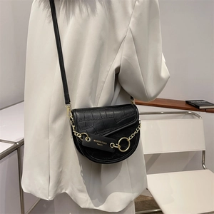 Chic black crocodile embossed saddle bag with gold chain strap on a cream blazer outfit