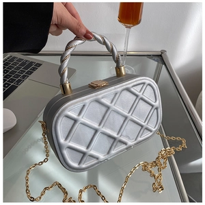Detail of silver quilted hard-shell clutch bag featuring a twisted handle and gold clasp