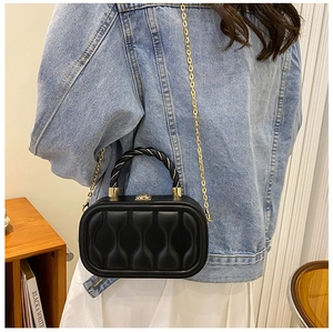 Mini black box bag with bow quilting and gold chain strap shown on a casual outfit