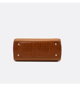 Detail view of the brown leather handbag base with crocodile texture and gold metal feet