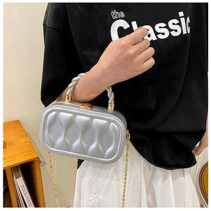 Detail of silver wavy clutch with spiral handle and gold chain strap on black t-shirt