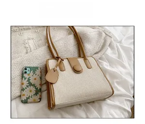 Close-up of beige pleated tote bag with brown trim and phone case for size reference