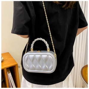 Silver mini box bag with wavy texture and gold chain strap worn by a model
