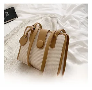Detail view of cream pleated fabric handbag with brown leather trim and round buckle clasp