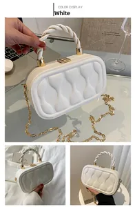 Detail of white box bag with 3D bow texture, gold hardware, and woven top handle