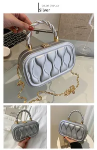 Detail of silver box clutch showing the wave relief texture and metallic twist handle