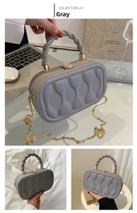 Detail of grey textured box bag with woven handle and gold chain strap close-up view