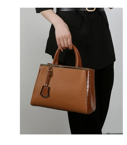 Dettaglio della borsa marrone con contrasto di texture in pelle litchi e coccodrillo