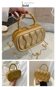 Detailed view of gold box evening bag with quilted texture and metal handle chain