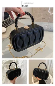 Detail of black quilted box bag with gold metal chain and braided handle texture