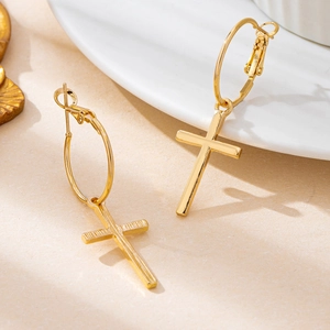 Minimalist gold cross pendant earrings with polished mirror finish on white plate