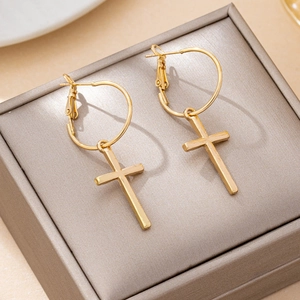 Polished gold cross pendant earrings displayed on a premium satin jewelry box