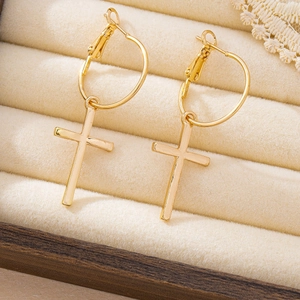 Vintage gold cross dangle hoop earrings displayed on a beige velvet jewelry box