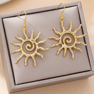 Détail macro de boucles d'oreilles soleil dorées avec texture spirale sur un écrin gris