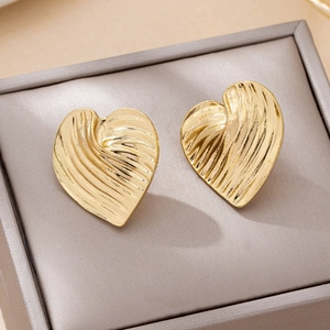 Golden heart earrings with 3D pleated wave texture presented in a gray jewelry box